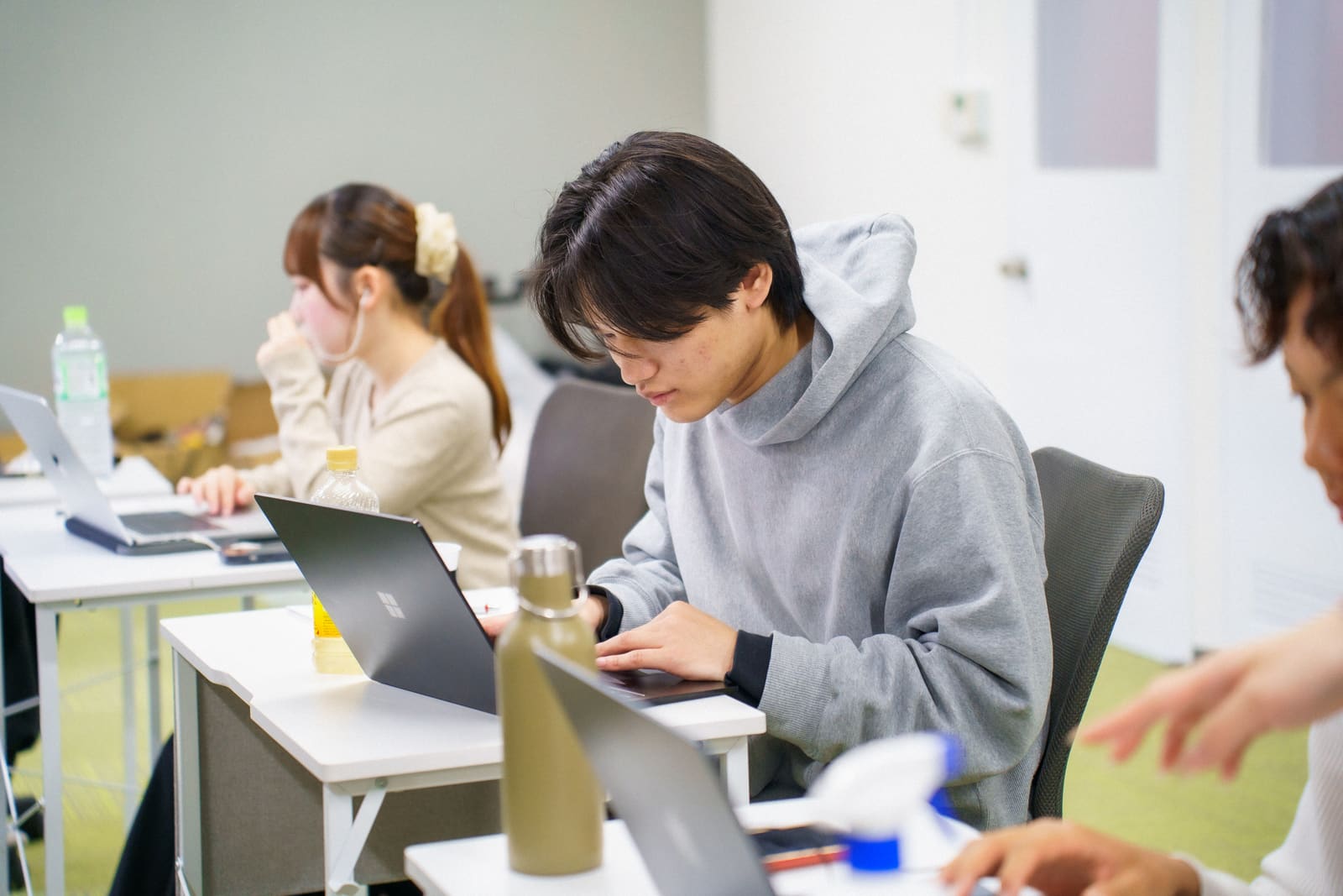 グレーのパーカーで、ノートPCに入力するメンバー