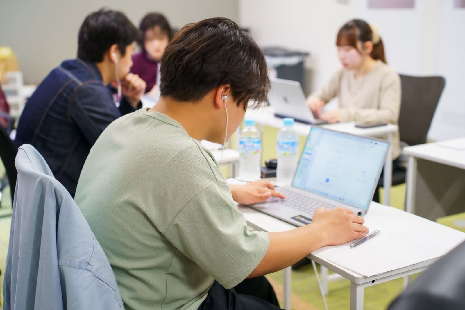 ミント色のTシャツのメンバーが入力し、奥で仲間が作業する